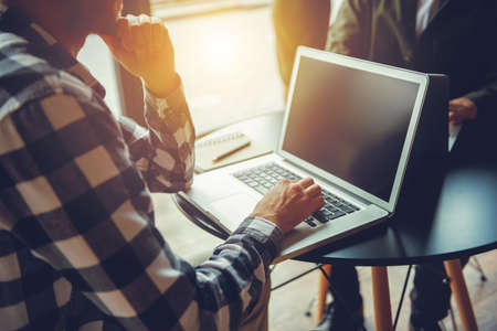Business man works with laptop on a table in a modern office near windowの写真素材
