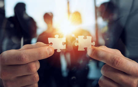 Businessman join two puzzle pieces. Concept of teamwork and partnership. double exposure with light effectsの写真素材