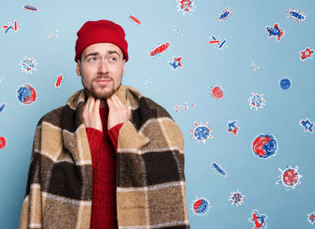 Boy caught a cold and is surrounded by viruses and bacteria. Studio on Cyan backgroundの写真素材