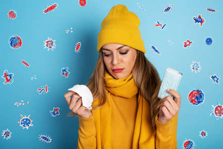 Girl caught a cold and is surrounded by viruses and bacteria. Studio on Cyan background