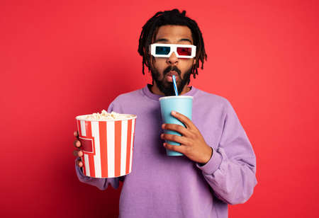 Boy has fun watching a film. Concept of entertainment and streaming tv. red background