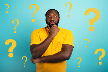 Confuse and pensive expression of a boy with many questions . cyan colored backgroundの写真素材