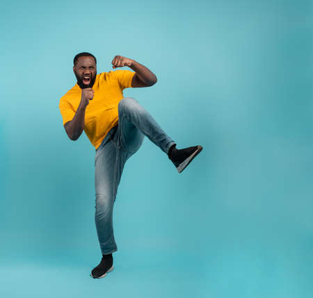 Man is angry and fights with kicks. Blue background.
