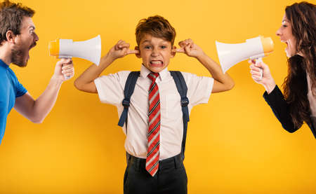 Student Child covers his ears because he does not want to hear reproach of the parents. Yellow backgroundの写真素材