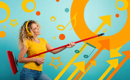 Girl with headset use the broom like a guitar. Cyan backgroundの写真素材