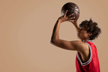 Basketball player throws the ball on brown background.の写真素材