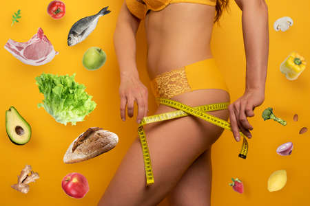 Girl measures with the meter the diet results. yellow backgroundの写真素材