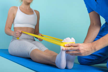 Girl performs exercises with a physiotherapist. Cyan background
