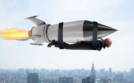 Businessman flies with a fast rocket. Concept of ambition and determinationの写真素材