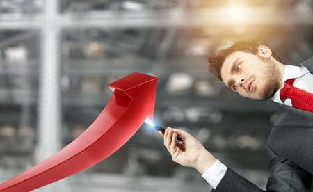 Businessman draws a growing red arrow of statisticの写真素材