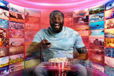 Boy has fun watching a film. Concept of entertainment and streaming tv. red background