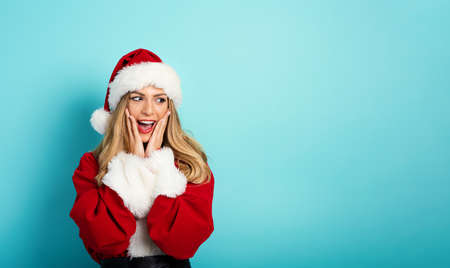 Woman with Santa Claus costume with surprised expression. cyan backgroundの写真素材
