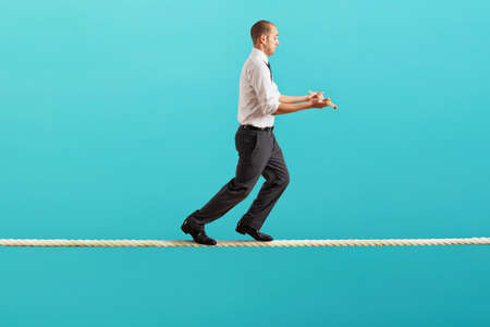 Worry man in balance walking on a ropeの写真素材