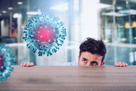 Man is afraid of the covid19 virus and he is hidden rear a deskの写真素材