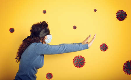 Woman with mask and blindfold. concept of uncertainty. yellow backgroundの写真素材