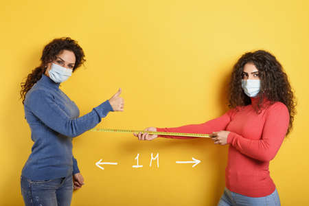 Friends keep distance between them of 1 meter. Concept of codiv-19 rules to avoid pandemic. yellow...