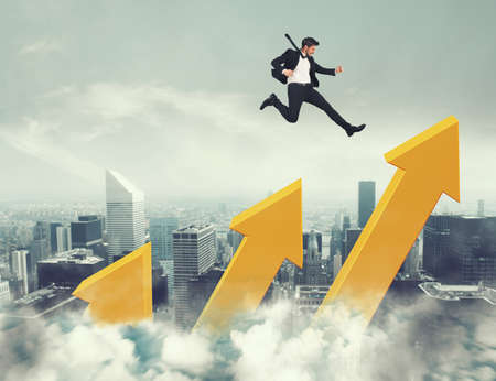Businessman jumps on increasing statistic arrows to reach the topの写真素材