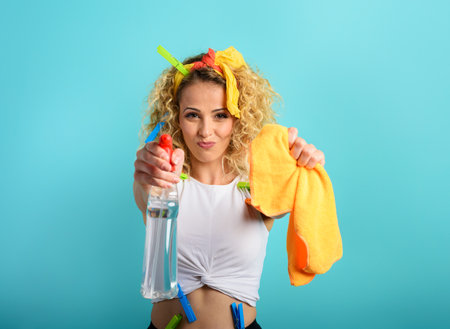 Blonde housewife splashs disinfectant to remove viruses and bacteria. Cyan background