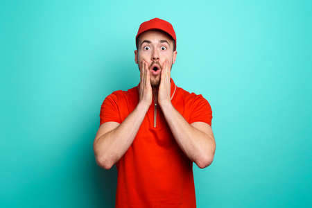 Courier with a wondered expression about a great promotion. cyan backgroundの写真素材