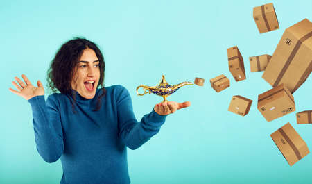 Woman is happy because she founds lamp of aladdin and receives a lot of packages. Cyan backgroundの写真素材