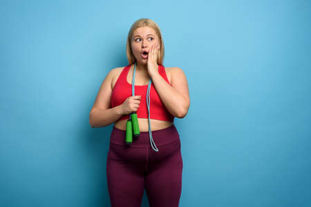 Fat girl does gym but is worried for something. cyan backgroundの写真素材
