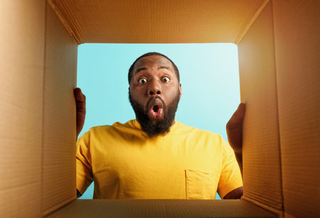 Happy man receives a package from online shop order. happy and surprised expression. Blue background.の写真素材