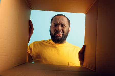 Man have doubt and he is disgusted about what is inside a package. concept of online shop fraudの写真素材