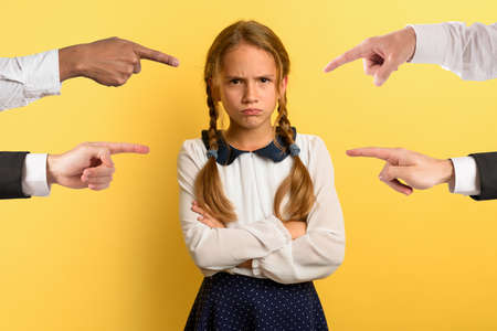 Young girl is unhappy and angry because she is accused. yellow backgroundの写真素材
