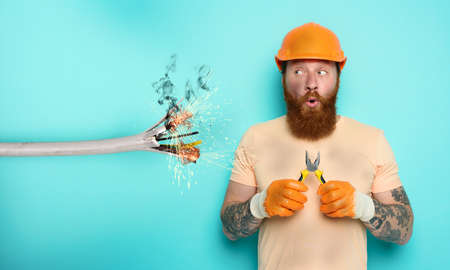 Incompetent worker electrician is unsure about his work. cyan backgroundの写真素材