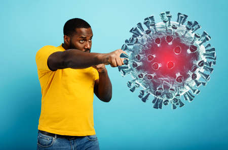 Man attacks with a punch the coronavirus. Blue backgroundの写真素材