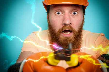 Incompetent worker electrician is unsure about his work. cyan backgroundの写真素材