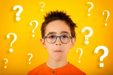 Child is not sure about something and has some questions. yellow backgroundの写真素材