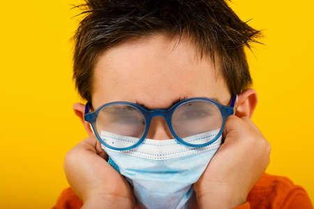 Child with fogged lens due to face maskの写真素材