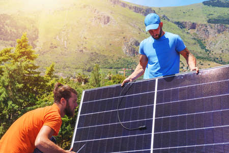 Workers assemble energy system with solar panel for electricity and hot water