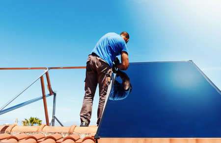Workers assemble energy system with solar panel hot water
