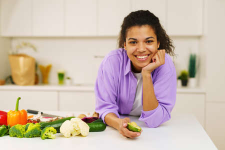 Young cook with apron prepares vegetables in the kitchenの写真素材