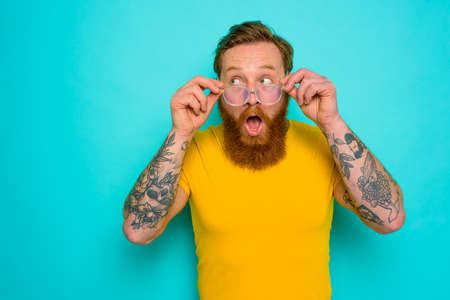 Man with yellow t-shirt and beard is shocked about somethingの写真素材