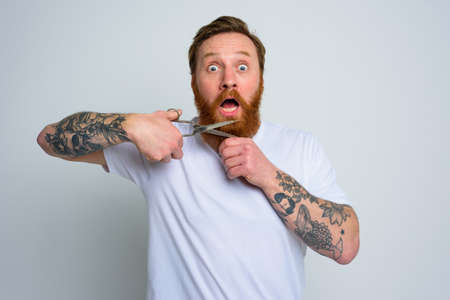 Amazed man with scissors doees not want to cut the beard