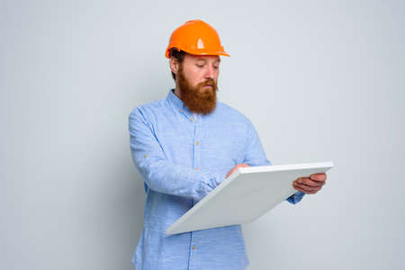 Confidant architect with beard and orange helmet does a sketchの写真素材