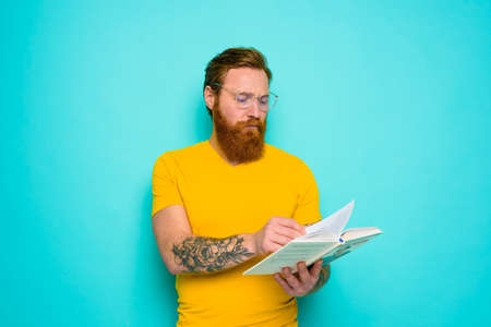 Man with yellow t-shirt reads a book