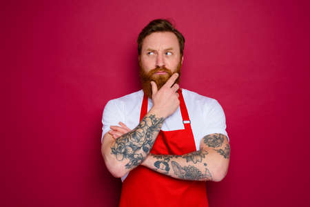 doubter isolated chef with beard and red apronの写真素材