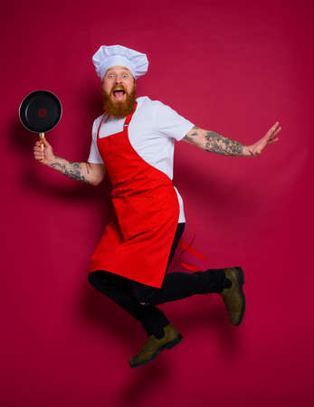 scared chef with beard and red apron jumpsの写真素材
