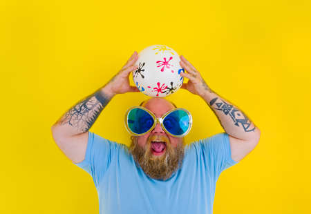 Fat man with beard and sunglasses have fun with a ballの写真素材