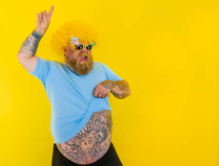 Fat man with wig in head and sunglasses dancesの写真素材