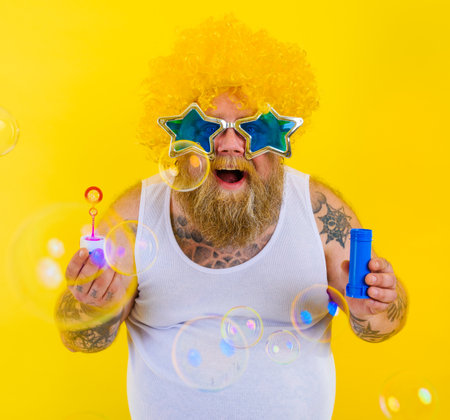 Amazed man with yellow wig in head play with bubbles soapの写真素材