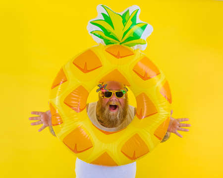 Fat amazed man with wig in head is ready to swim with a donut lifesaverの写真素材