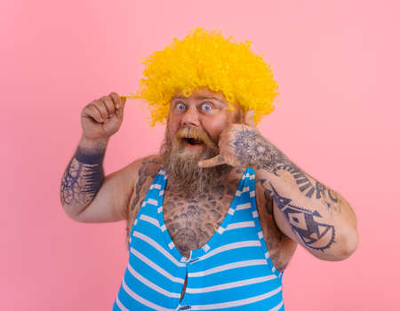 Amazed man with yellow wig and swimsuit is ready to the summerの写真素材