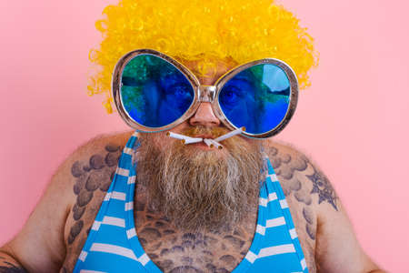 Fat serious man with beard and wig smokes cigarettes