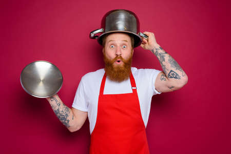 wondered chef with beard and red apron plays with potの写真素材