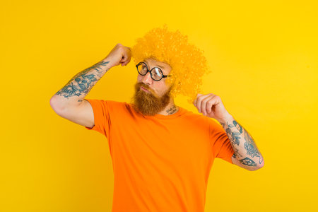 Thoughtful man with beard, yellow wig and glassesの写真素材